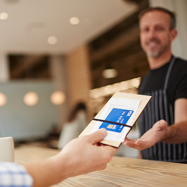 Man handing his credit card in check tray to waiter.
