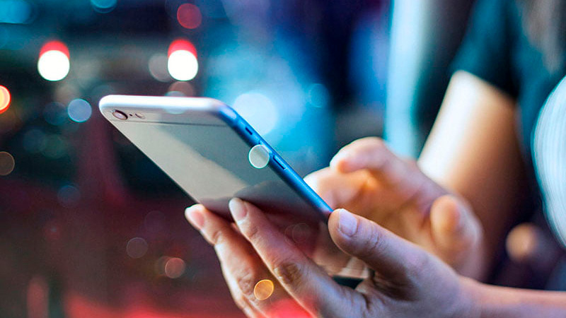 Persona sosteniendo un celular con fondo difuminado